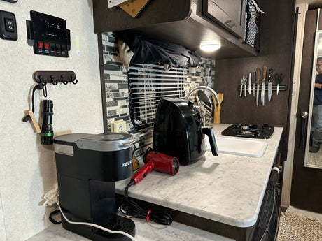 Inside an RV rental kitchen, featuring a Keurig, air fryer, stove, sink, and magnetic knife strip.