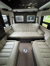 Spacious RV rental interior with cream-colored seating: a long rear sofa and two front chairs, perfect for comfortable road trips.
