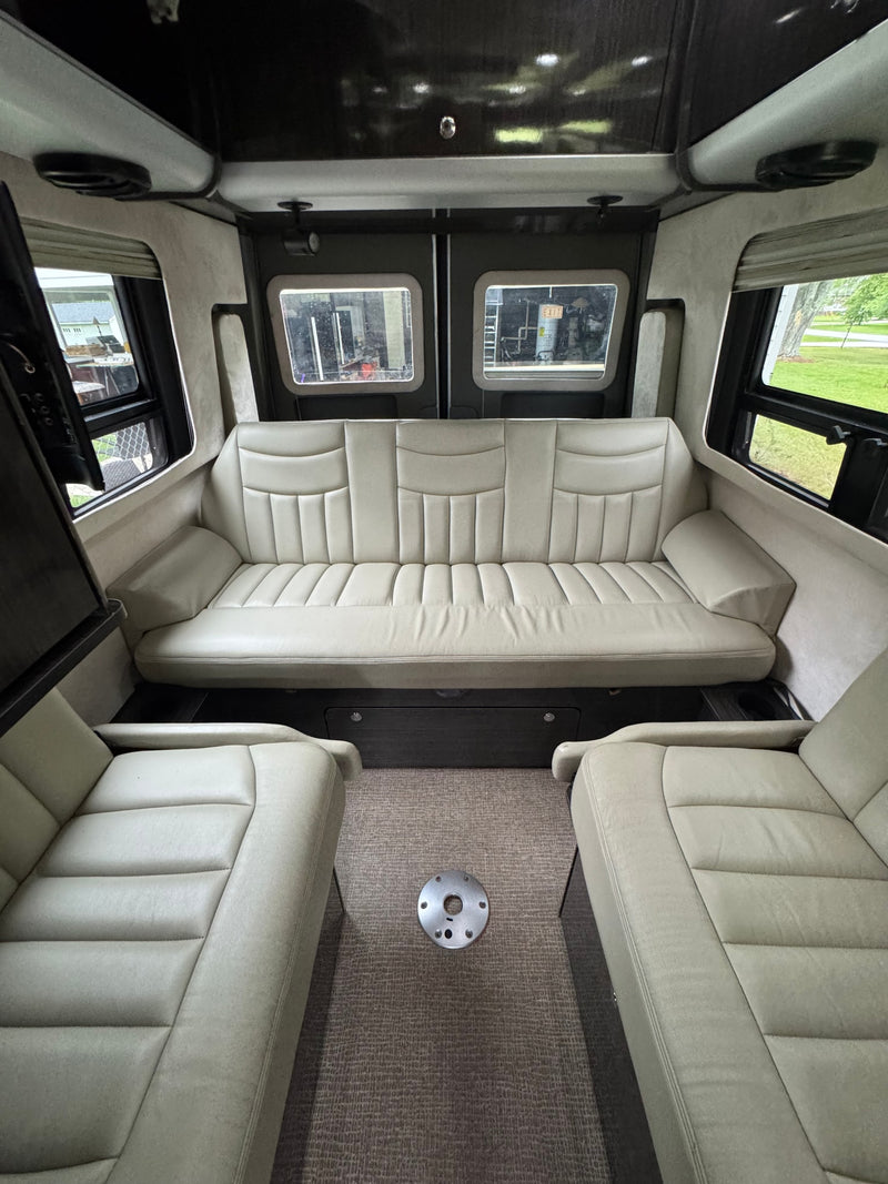 Spacious RV rental interior with cream-colored seating: a long rear sofa and two front chairs, perfect for comfortable road trips. — photo 3