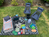 Essential gear for your RV rental adventure! This photo displays chairs, kitchenware, and camping supplies neatly arranged on a mat outdoors.