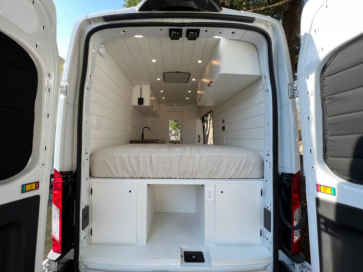 Step inside this white rv rental camper van! Features a cozy bed, sleek mini-kitchen, and smart storage for your adventures. — photo 8