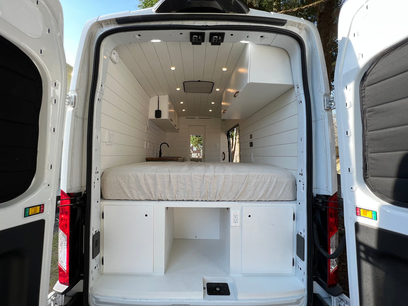 Step inside this white rv rental camper van! Features a cozy bed, sleek mini-kitchen, and smart storage for your adventures. — photo 8