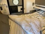 **RV rental** interior: a bed with patterned sheets, overhead cabinets, screen door with round window, and a "bean • THERE" sign.