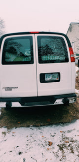 Rear of a white Chevy Express van, a versatile RV rental option, parked on snowy ground with a New Hampshire plate.