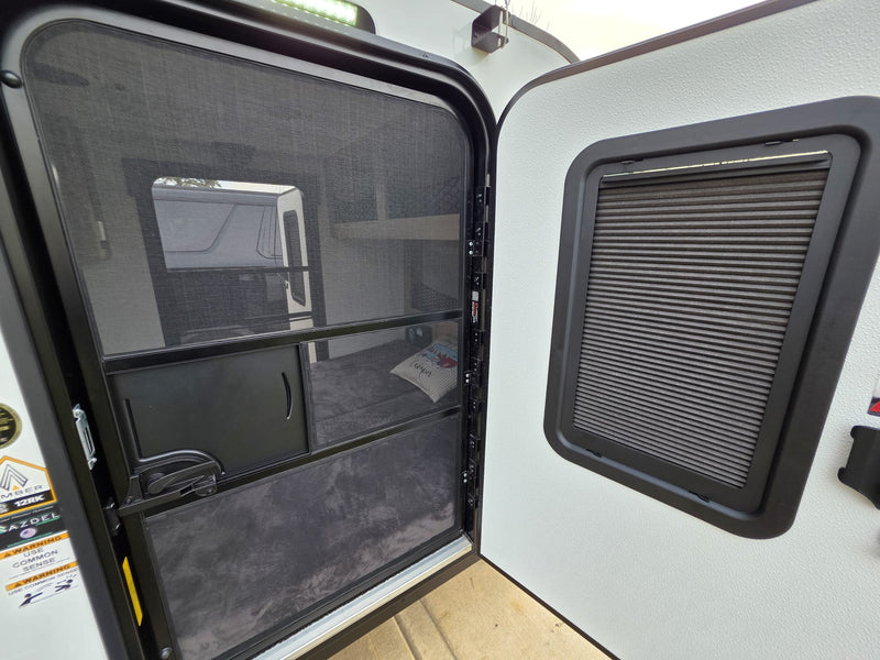 RV rental interior view: open screen door with outside visible, beside a window with a closed privacy blind. — photo 9