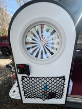 Explore compact RV rentals: A white teardrop camper's rear door open, featuring a window and built-in storage net.