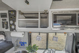 An rv rental's organized interior: kitchen sink, microwave, overhead storage, and a 'Remote Vans' control panel.