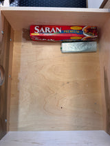 An RV rental's kitchen drawer neatly stores Saran Premium Wrap and plastic bags, essential for travel.