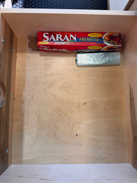An RV rental's kitchen drawer neatly stores Saran Premium Wrap and plastic bags, essential for travel.