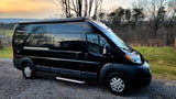 Experience adventure with this sleek black RV rental, a Sunlight Van Two camper van parked on gravel with a scenic backdrop.