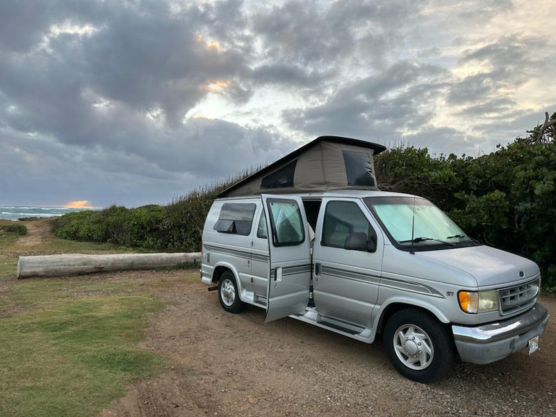 Silver pop-top RV rental parked by the ocean at sunset, ideal for beach camping adventures. — photo 4