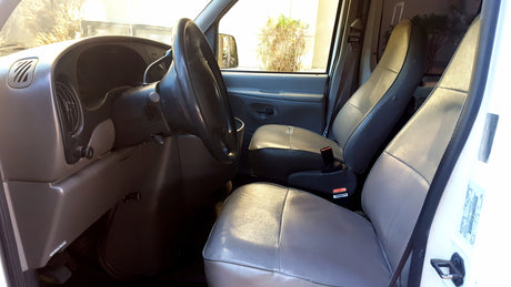 Interior of an rv rental van. View of grey driver's and passenger's seats, steering wheel, and dashboard from the front.