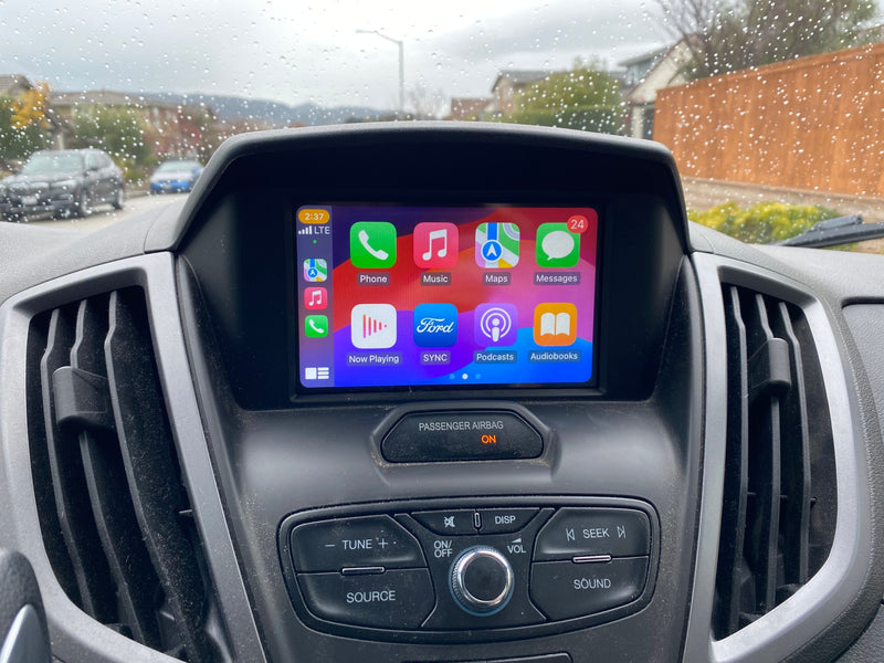 Inside a Ford RV rental, the Apple CarPlay screen displays apps while raindrops dot the windshield on a cloudy day. — photo 14