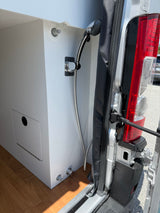 RV rental: Camper van interior showing a pull-out shower, water fill port, and integrated utility access panel.