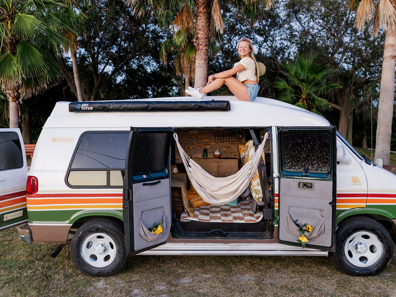 Woman atop a vibrant retro rv rental camper van — photo 1