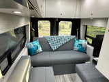 Cozy RV rental interior with a gray sofa, blue accents, and panoramic outdoor views, offering a comfortable mobile living space.