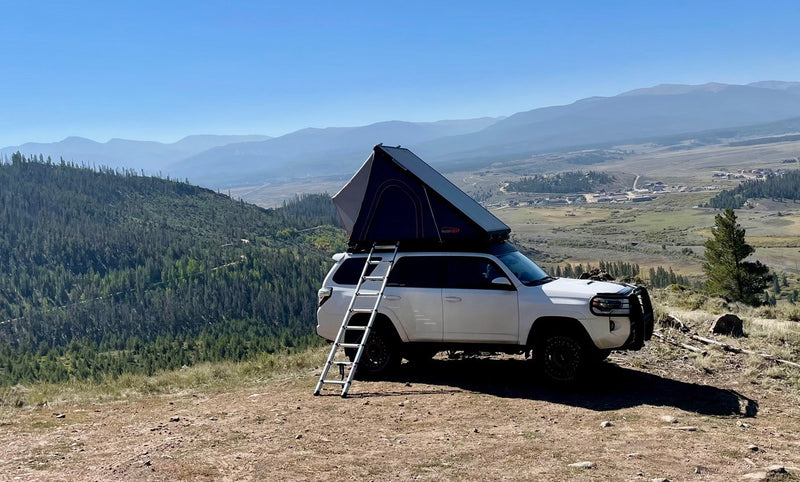 Adventure awaits! This white SUV with a rooftop tent, available for RV rental, offers elevated camping in the mountains with stunning valley views. — photo 10