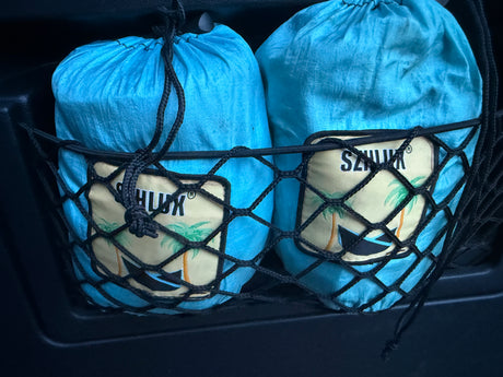 Two blue SZNJUK brand bags with palm tree logos are neatly stowed in a black net pocket, perfect for RV rental organization.