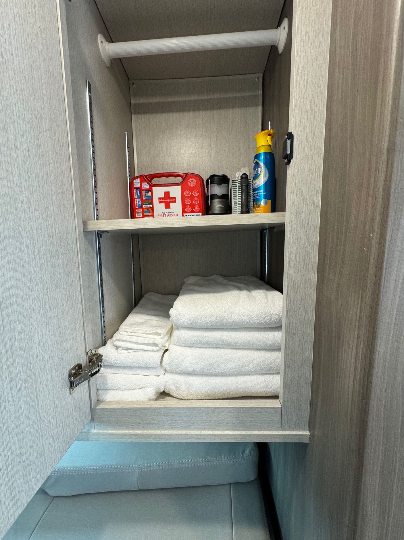 Well-stocked RV rental storage featuring a first aid kit, Pledge spray, and