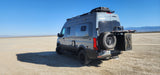 A gray Revel 4x4 camper van, perfect for an rv rental adventure, parked on a wide desert playa under a clear blue sky.