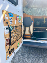 The customized door of an rv rental features a wooden panel with numerous outdoor adventure stickers and a practical storage net.