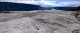 Yellowstone's Mammoth Hot Springs: Vast, textured terraces with rising steam and distant mountains. Explore by RV rental.