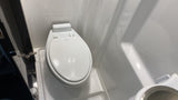 Bright white compact bathroom in an RV rental, featuring a Dometic toilet and a small sink.