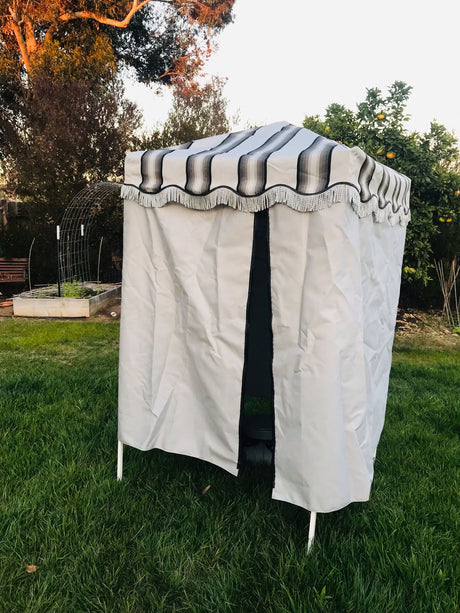 Portable outdoor shower/changing tent with a striped, fringed roof, great for RV rental adventures.