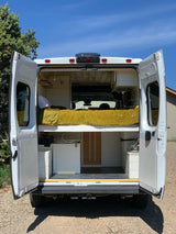 Rear view of a custom camper van, doors open. This cozy RV rental features a raised bed, kitchen, and smart storage.