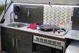 Convenient outdoor kitchen in an RV rental with sink, stove, microwave, and cabinets, ready for your camping trips.