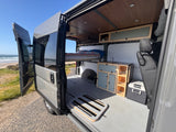Enjoy beachside living in this rv rental camper van. Features include an elevated bed, kitchen, and ample storage.
