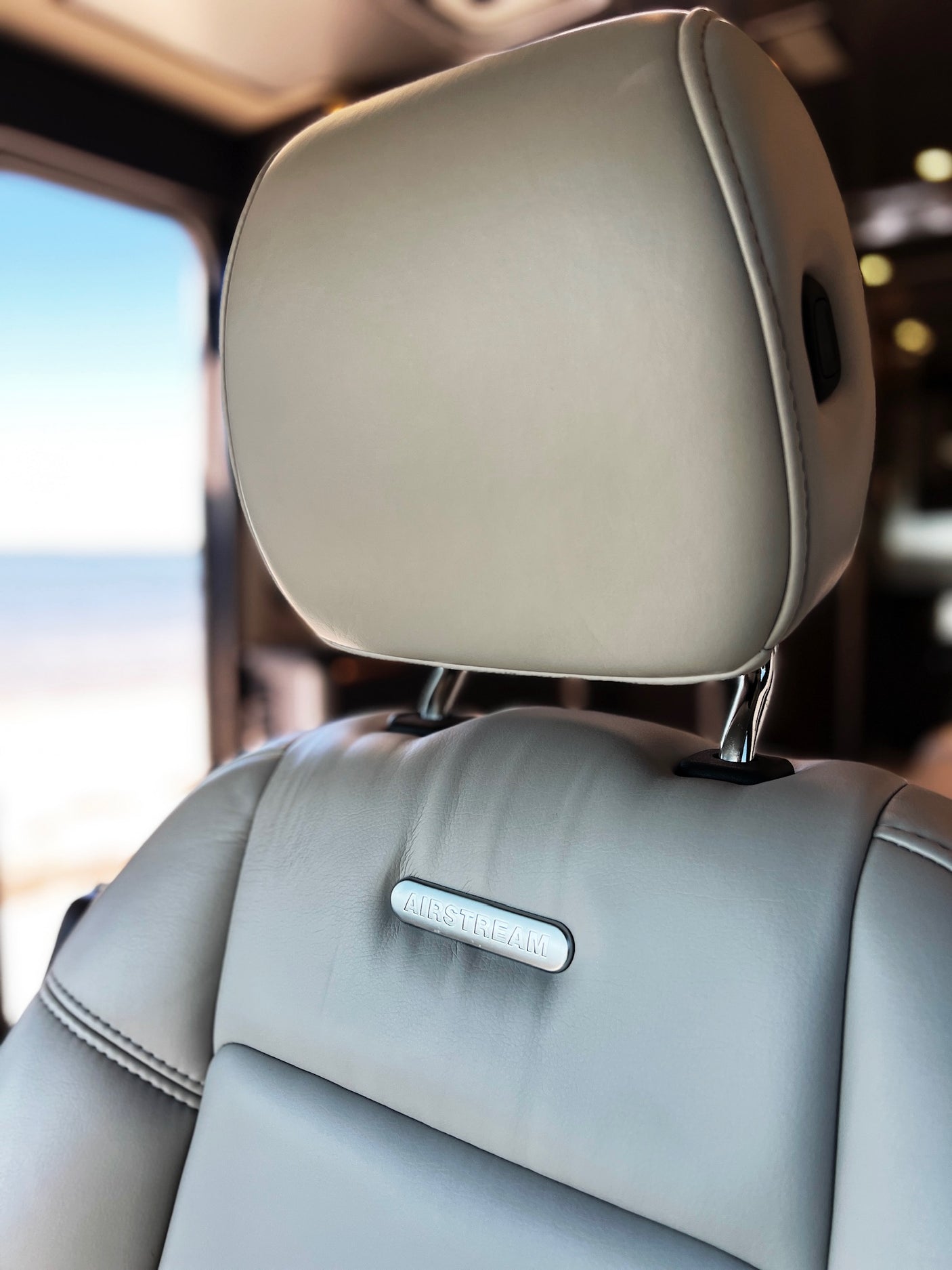 Airstream RV rental interior: Light leather seat with Airstream logo, scenic view from window. Perfect for road trips!