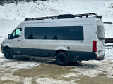 Silver Airstream Interstate X 4x4 RV rental van with roof rack, parked in a snowy landscape, ready for adventure.