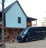 Black Mercedes Sprinter rv rental van parked at a modern light blue cabin for a scenic getaway.