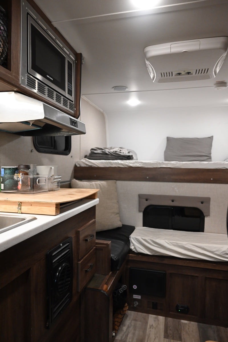  next to a seating area and elevated bunk bed.|Cozy RV rental interior with bunk bed — photo 8
