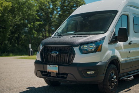 This white Ford Transit campervan, with its rugged black hood, is ready for your RV rental adventure.