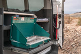 A Coleman propane stove slides out from an RV rental van, ready for outdoor cooking. Essential gear for desert camping adventures.