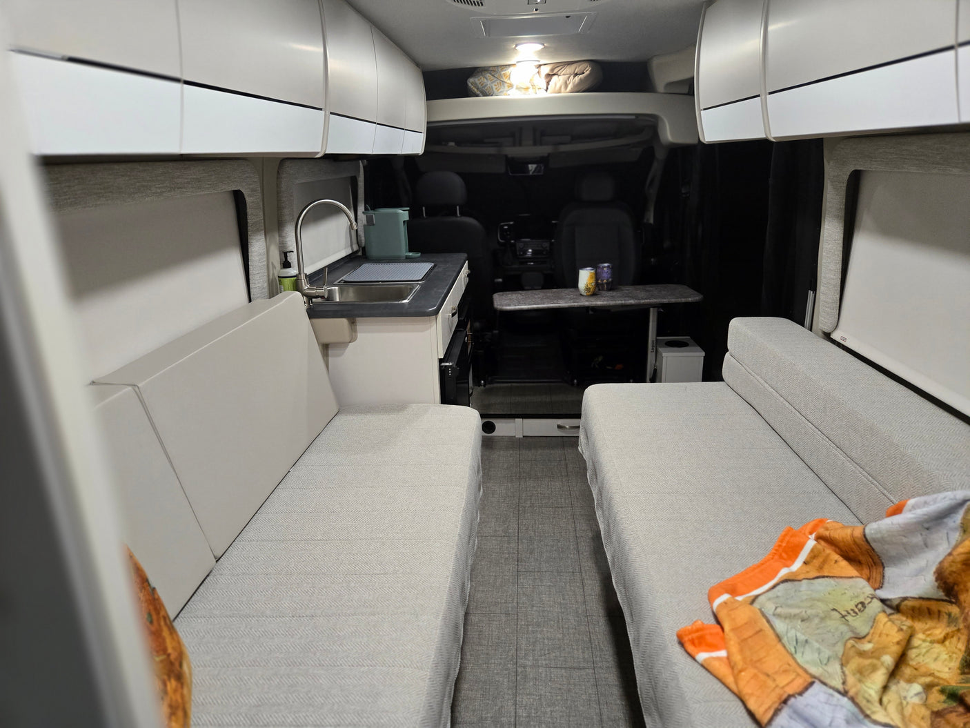Spacious rv rental interior features a compact kitchen, comfy facing benches, overhead storage, and adjustable table.