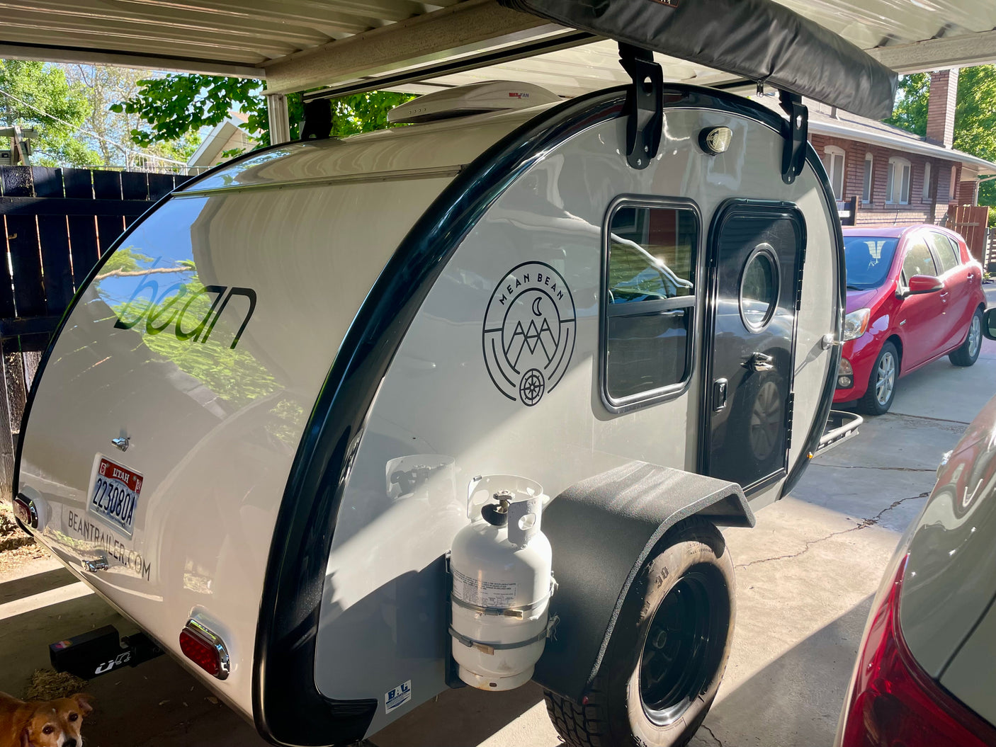Stylish Bean teardrop camper with all-terrain tires and propane tank, ideal for your next RV rental or personal outdoor adventure.