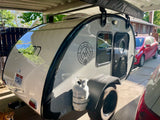 Stylish Bean teardrop camper with all-terrain tires and propane tank, ideal for your next RV rental or personal outdoor adventure.