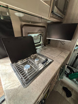 Well-equipped RV rental kitchen: two-burner stove, sink, ample counter space, and a mounted TV for your journey.