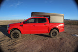 Red Ford Ranger pickup truck with a Tune camper, parked in a desert landscape. Perfect overland rv rental for off-road adventures.