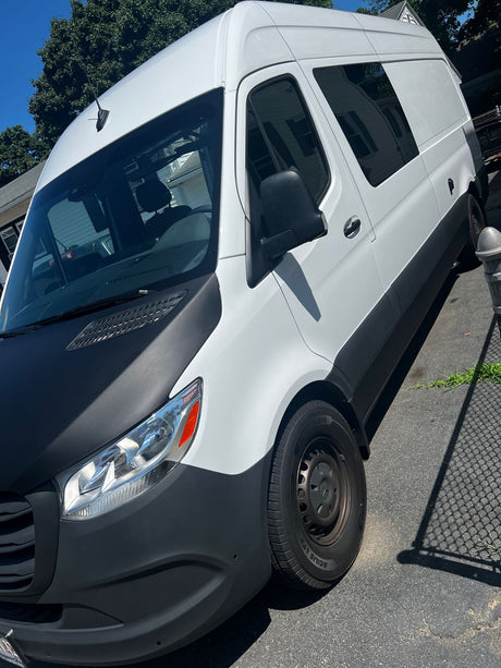 White and black high-roof cargo van, frequently used for rv rental conversions, parked on a sunny day.