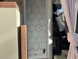 RV rental shower: a modern, compact bathroom with stylish hexagonal tiles, next to the van's main cabin.