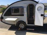 A classic teardrop trailer, ready for rv rental, features an open door, side window, and fold-down table.