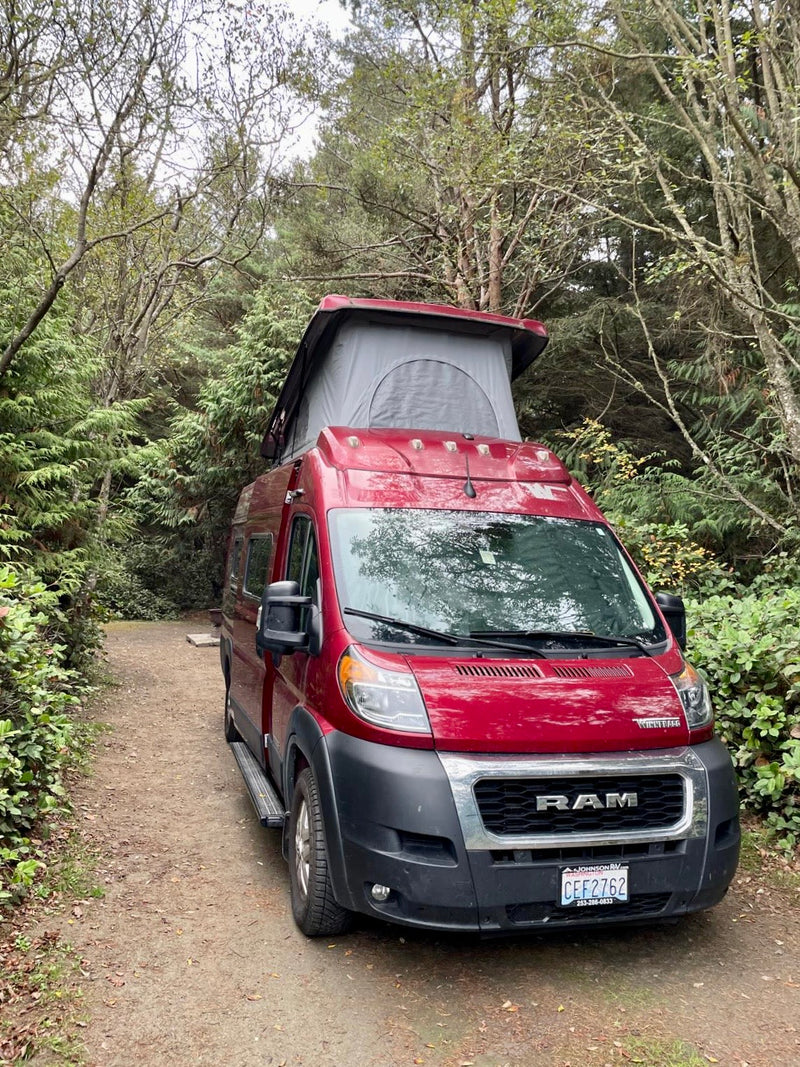 Red RV rental camper van with pop-top tent, parked on a forest path for wilderness camping. — photo 2