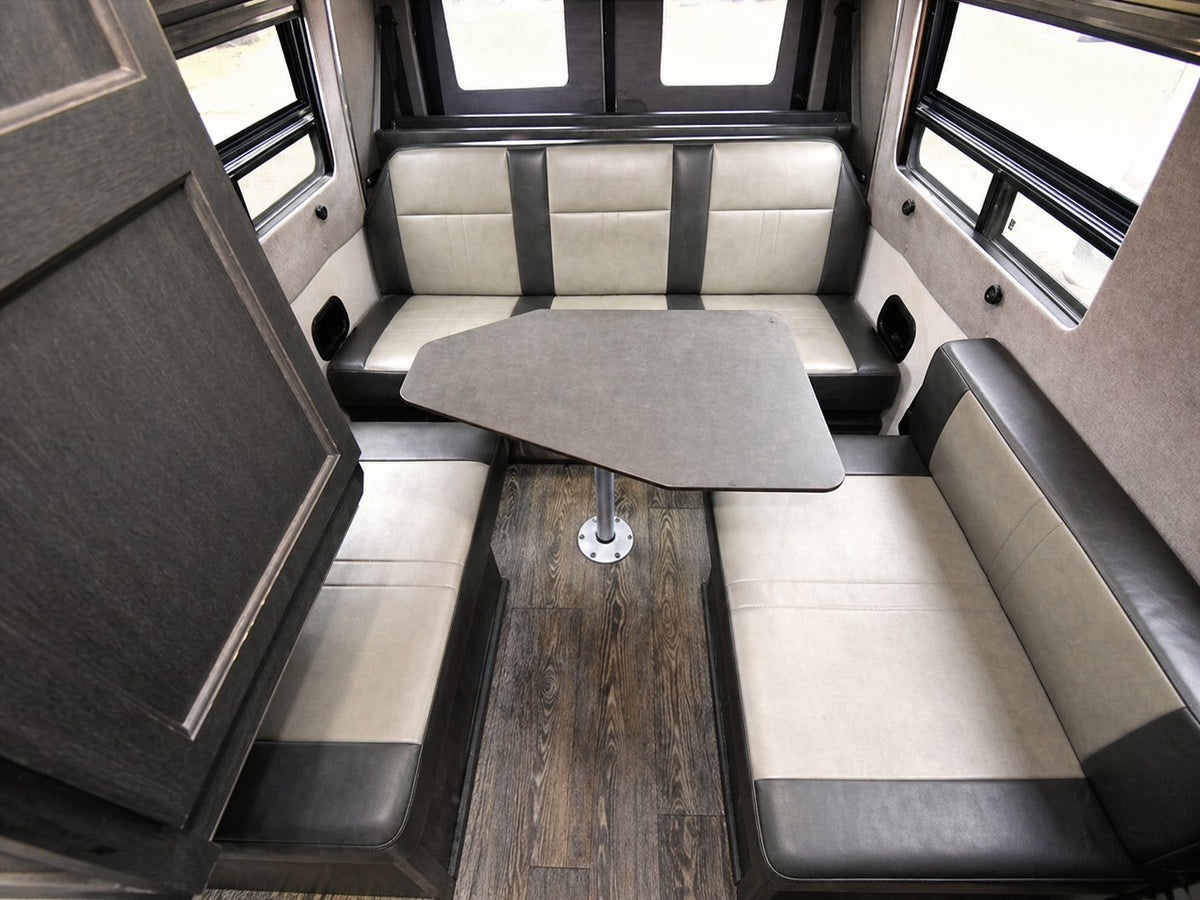 Spacious RV rental dinette area with comfortable two-tone bench seating and a gray table, ideal for meals or work. — photo 4
