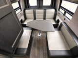 Spacious RV rental dinette area with comfortable two-tone bench seating and a gray table, ideal for meals or work.