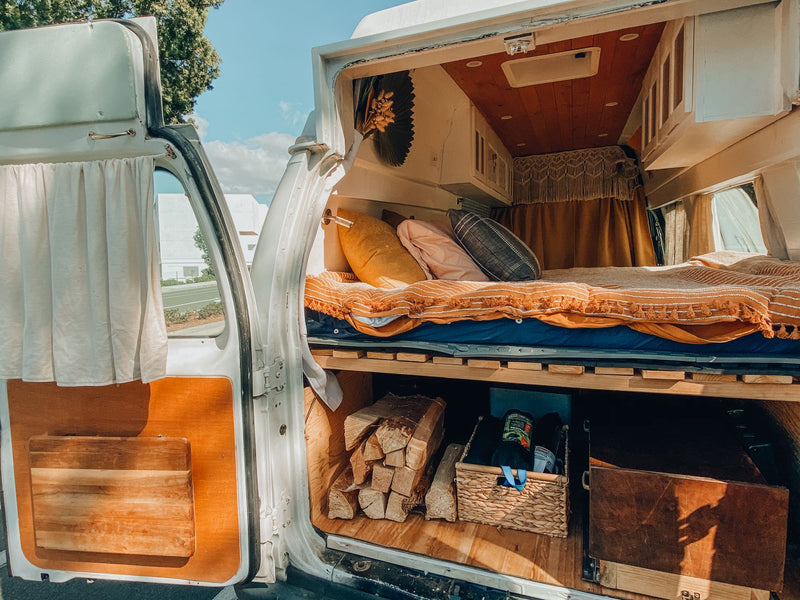 Explore this cozy camper van interior, perfect for an rv rental adventure! Features a bed above clever storage for firewood & gear. — photo 4