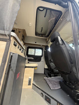 This RV rental offers a cozy interior: swiveling front seats, compact storage, a control panel, and a ceiling vent.